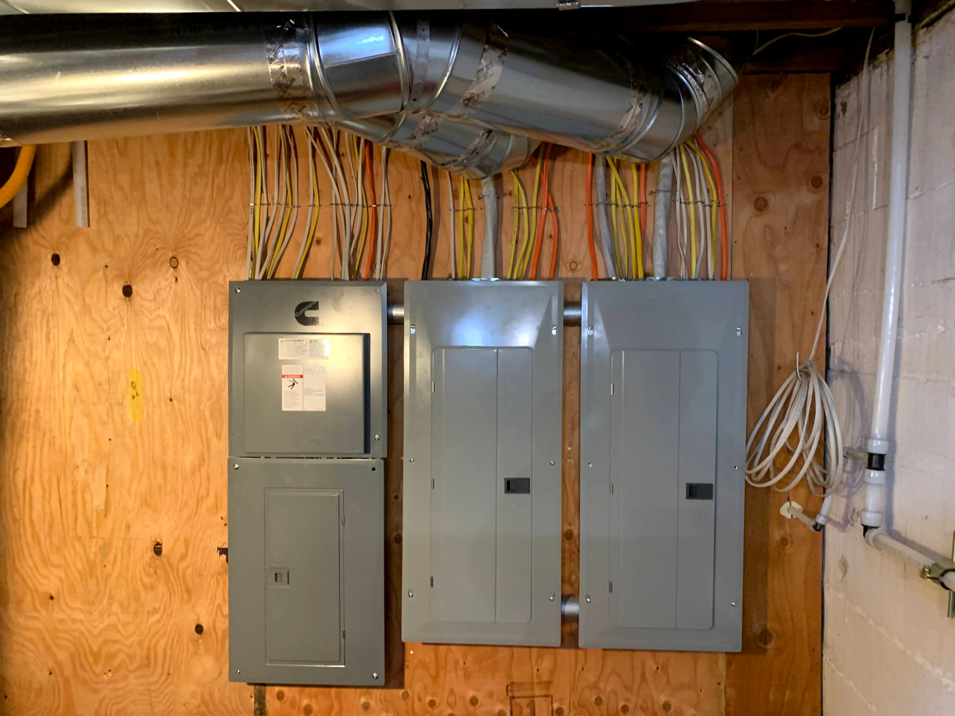 Three electrical panels and a transfer switch mounted on plywood