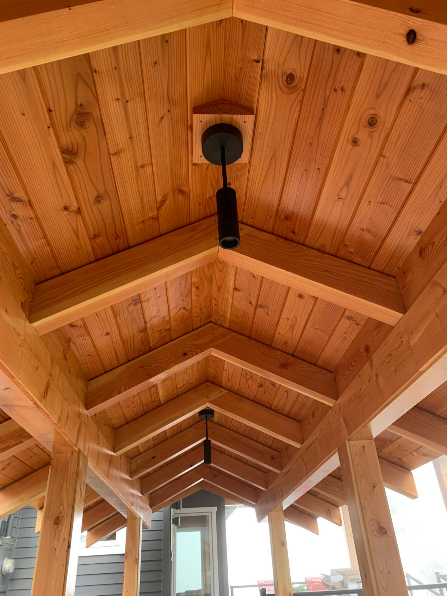 Pendant lighting under a pitched wooden patio cover